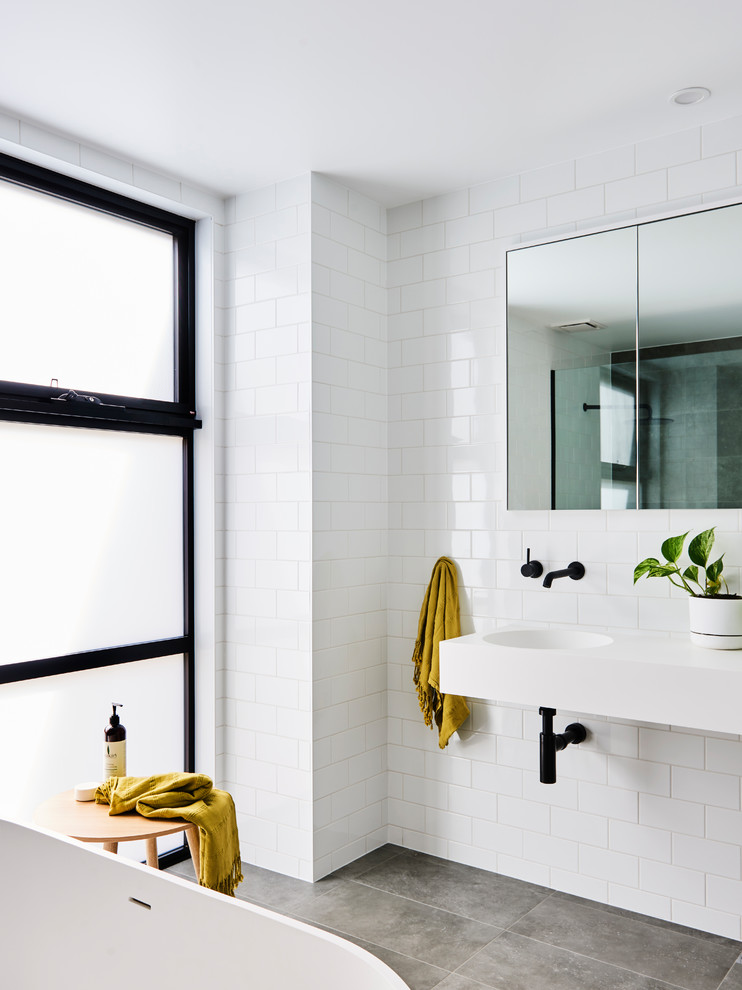 Photo of a mid-sized modern master bathroom in Other with flat-panel cabinets, white cabinets, a freestanding tub, an open shower, white tile, subway tile, white walls, porcelain floors, an integrated sink, engineered quartz benchtops, grey floor, an open shower and white benchtops.
