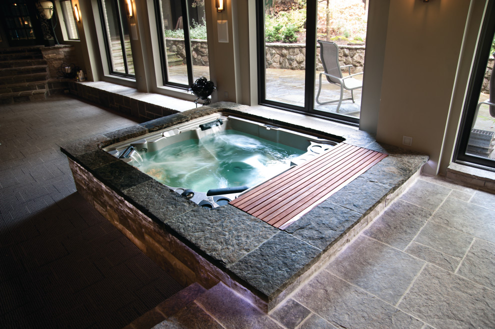 Aménagement d'une piscine intérieure hors-sol moderne avec un bain bouillonnant et des pavés en pierre naturelle.