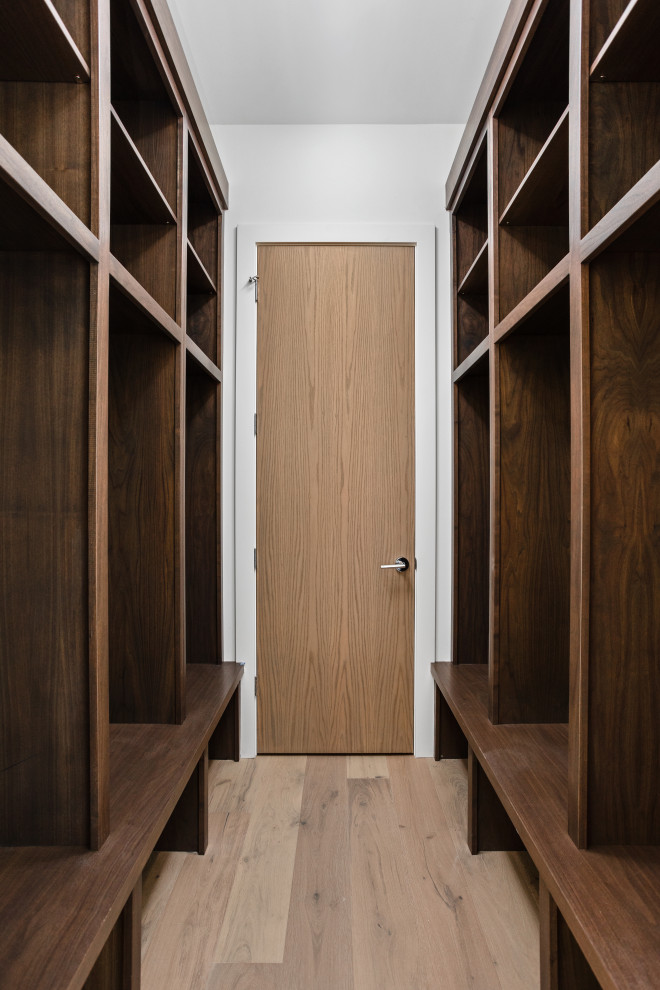 Cette photo montre un grand dressing moderne en bois brun neutre avec un placard sans porte, parquet clair et un sol multicolore.