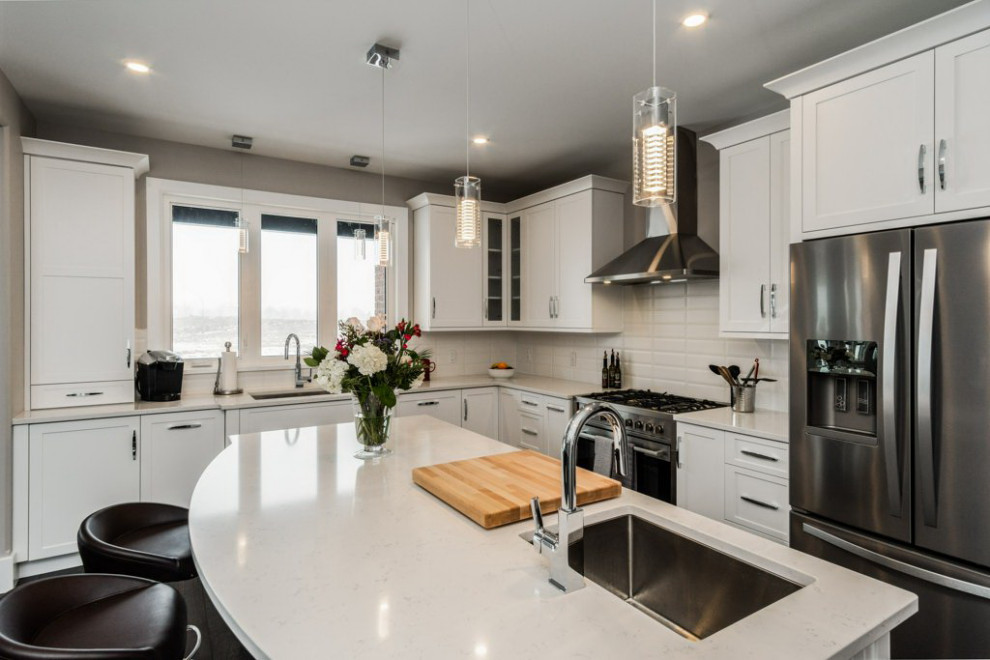 Inspiration for a mid-sized transitional l-shaped dark wood floor and brown floor open concept kitchen remodel in Ottawa with an undermount sink, shaker cabinets, white cabinets, quartz countertops, white backsplash, subway tile backsplash, stainless steel appliances, an island and white countertops