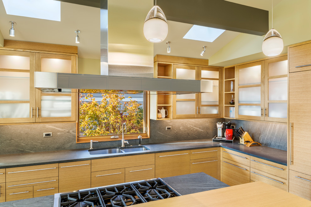 Photo of a contemporary l-shaped separate kitchen in Seattle with a double-bowl sink, flat-panel cabinets, light wood cabinets, grey splashback, with island, granite benchtops, stone slab splashback and stainless steel appliances.