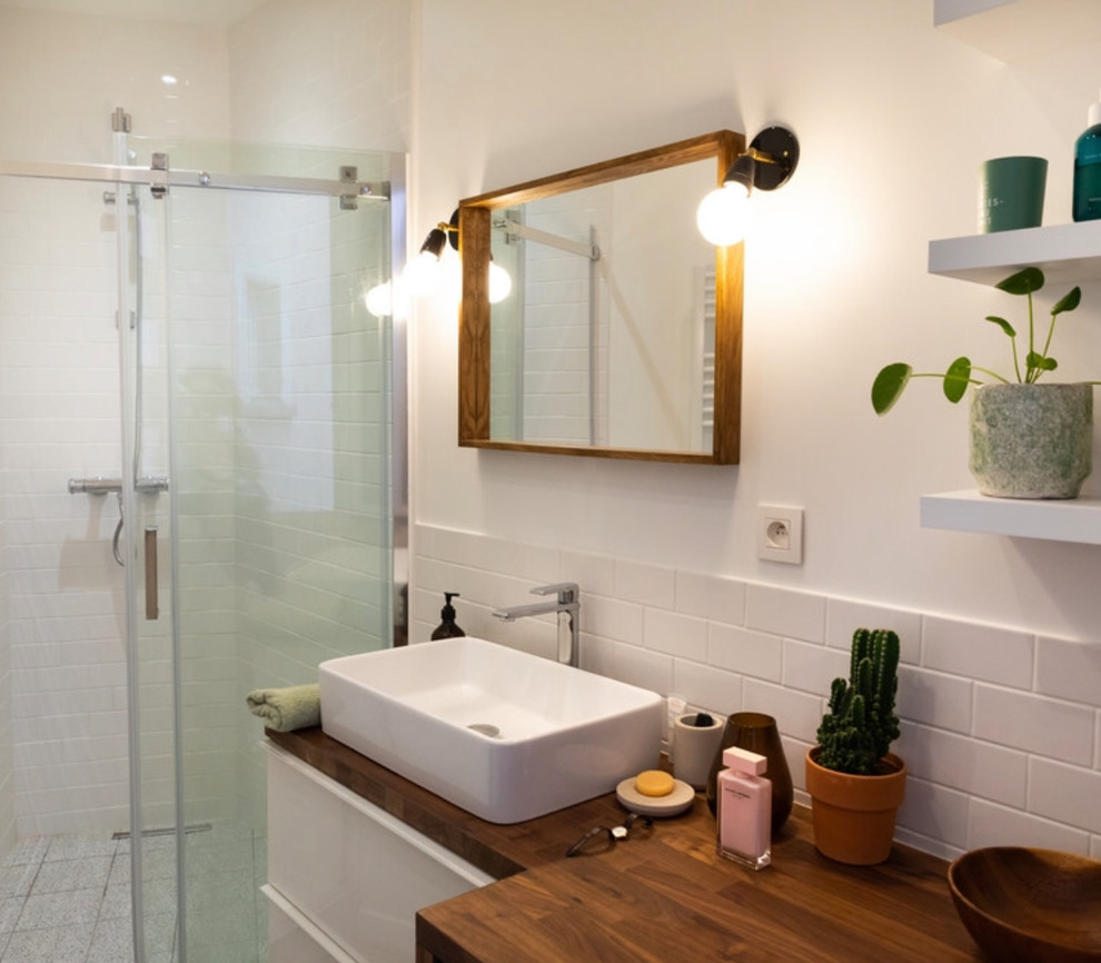 Design ideas for a mid-sized midcentury master bathroom in Paris with white cabinets, a curbless shower, white tile, subway tile, white walls, a sliding shower screen, ceramic floors, a console sink, wood benchtops, grey floor and brown benchtops.