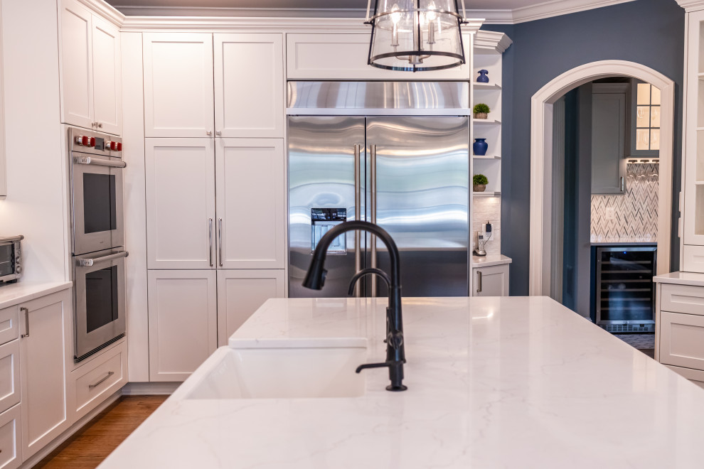 Eat-in kitchen - large transitional u-shaped medium tone wood floor and brown floor eat-in kitchen idea in Baltimore with a farmhouse sink, shaker cabinets, blue cabinets, quartz countertops, white backsplash, marble backsplash, stainless steel appliances, an island and white countertops