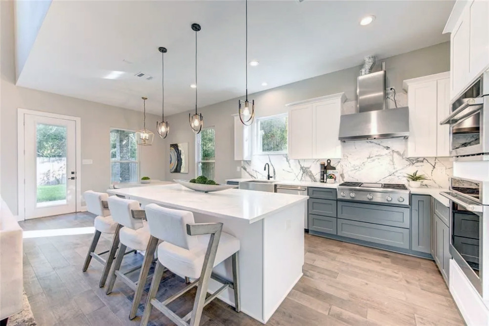 Inspiration for a large light wood floor and beige floor eat-in kitchen remodel with marble countertops, marble backsplash, stainless steel appliances and an island