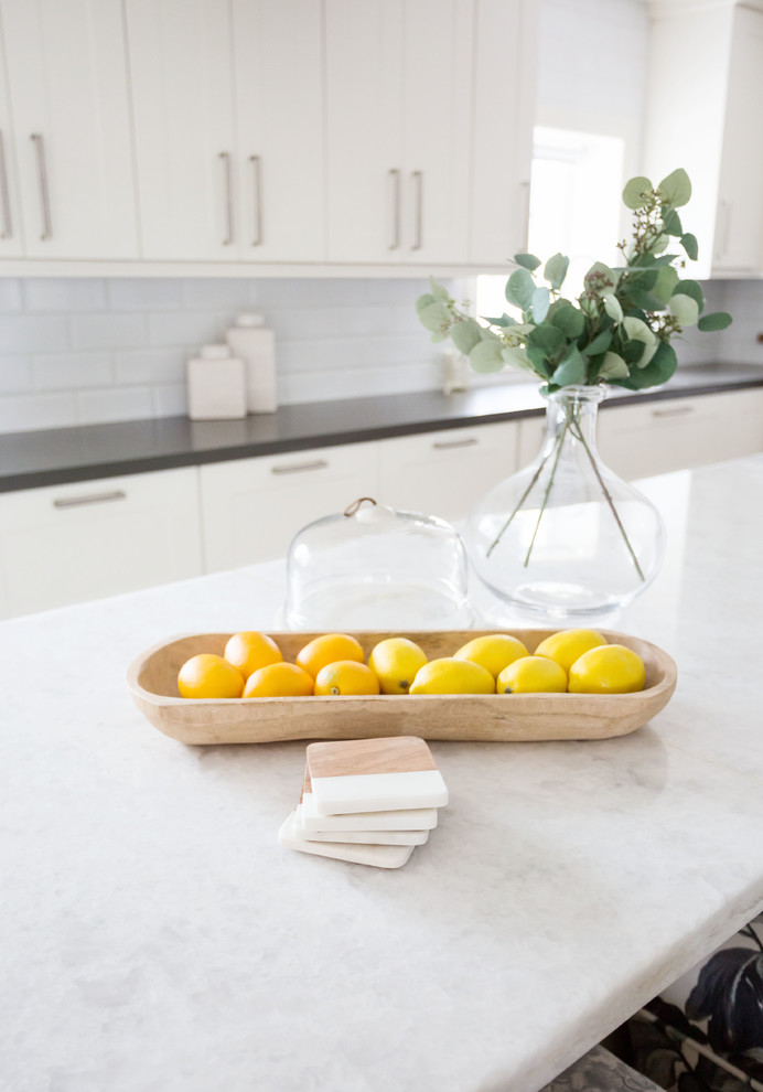 Eat-in kitchen - large transitional u-shaped light wood floor and brown floor eat-in kitchen idea in Phoenix with a farmhouse sink, recessed-panel cabinets, white cabinets, quartz countertops, white backsplash, subway tile backsplash, stainless steel appliances, an island and white countertops