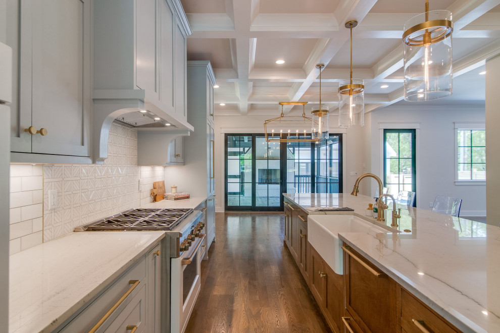 This is an example of a large classic galley open plan kitchen in Nashville with a belfast sink, shaker cabinets, grey cabinets, quartz worktops, white splashback, stone tiled splashback, white appliances, medium hardwood flooring, an island, brown floors, grey worktops and a coffered ceiling.