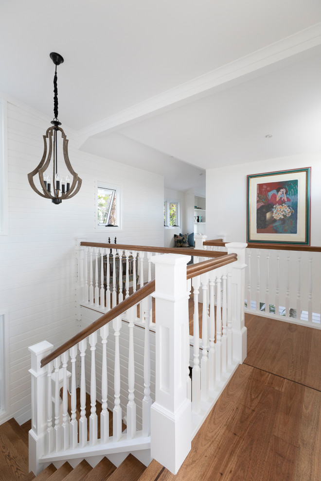 Design ideas for a mid-sized tropical wood u-shaped staircase in Sunshine Coast with painted wood risers and wood railing.