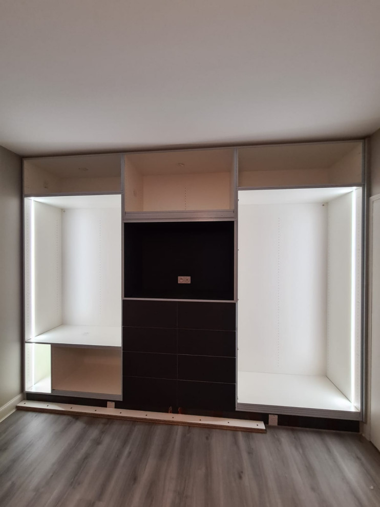 Immagine di una grande cabina armadio unisex minimalista con ante a filo, ante grigie, pavimento in laminato e pavimento marrone