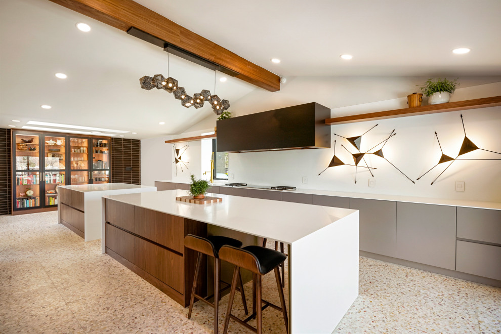 This is an example of an expansive midcentury single-wall kitchen pantry in Denver with an integrated sink, flat-panel cabinets, medium wood cabinets, quartz benchtops, white splashback, panelled appliances, multiple islands, white benchtop and exposed beam.