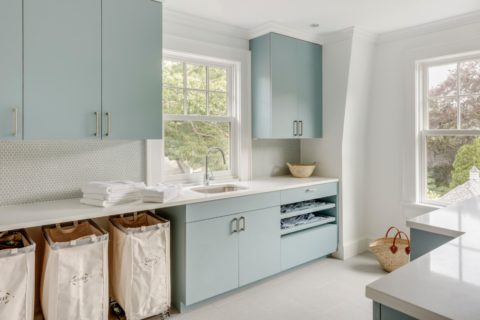 Large beach style galley separated utility room in Boston with a single-bowl sink, flat-panel cabinets, turquoise cabinets, quartz worktops, blue splashback, glass tiled splashback, white walls, porcelain flooring, a concealed washer and dryer and white worktops.
