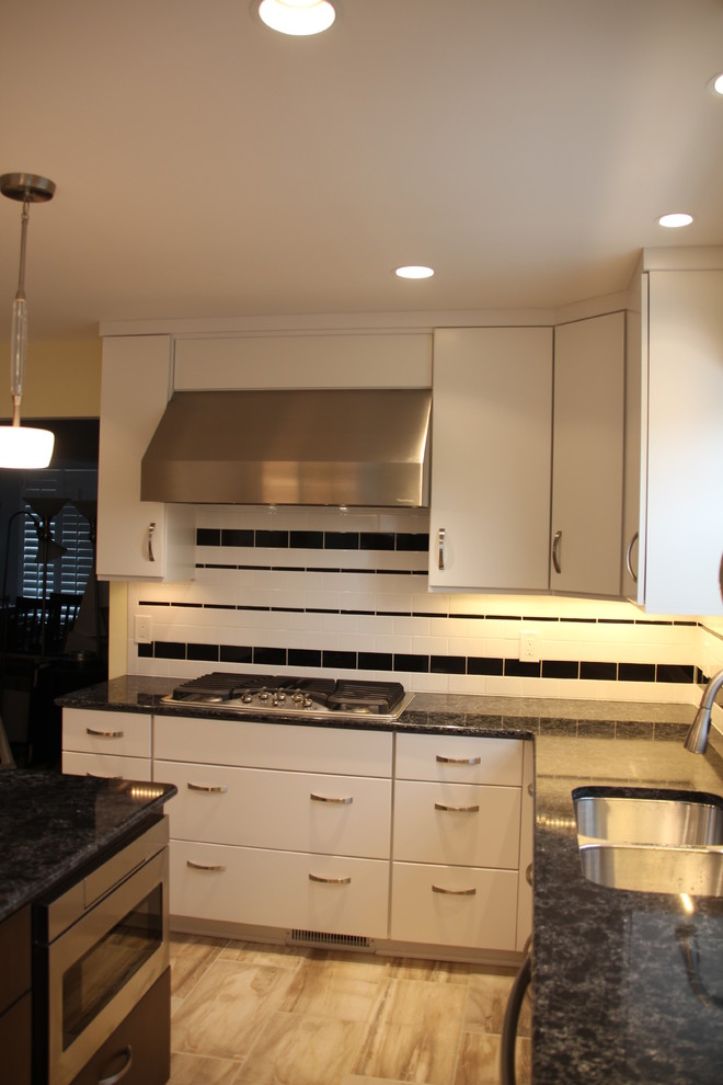 Eat-in kitchen - mid-sized transitional u-shaped porcelain tile and beige floor eat-in kitchen idea in DC Metro with an undermount sink, flat-panel cabinets, white cabinets, quartz countertops, white backsplash, ceramic backsplash, stainless steel appliances, an island and black countertops