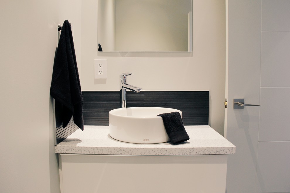 This is an example of a small modern powder room in Other with a vessel sink, flat-panel cabinets, white cabinets, solid surface benchtops, a one-piece toilet, black tile, ceramic tile and grey walls.