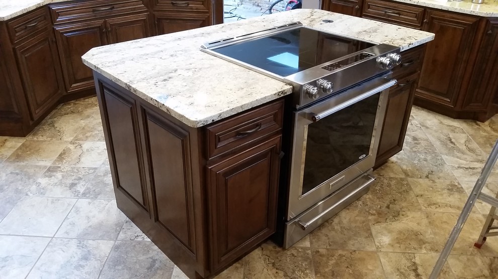 Kitchen - large traditional u-shaped ceramic tile kitchen idea with raised-panel cabinets, medium tone wood cabinets, granite countertops, stainless steel appliances, two islands and a farmhouse sink