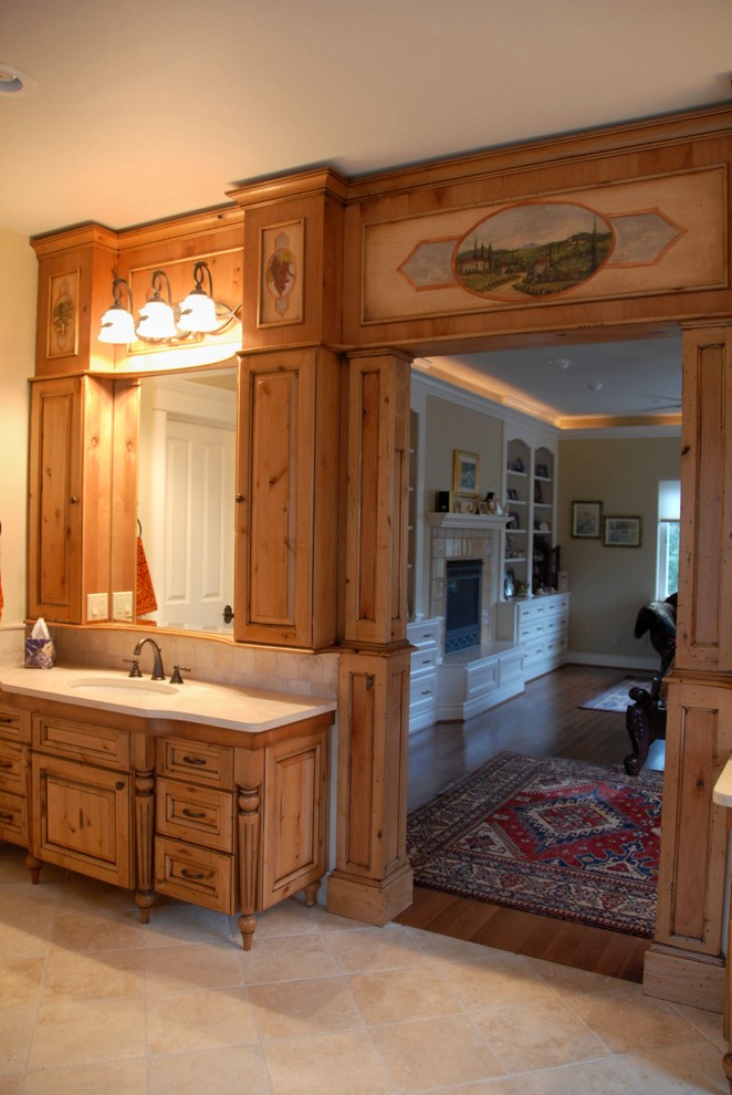 Example of a large mountain style master travertine floor and beige floor bathroom design with raised-panel cabinets, light wood cabinets, beige walls, an undermount sink and quartz countertops