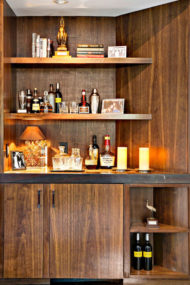 This is an example of a small transitional home bar in New York with dark wood cabinets and carpet.