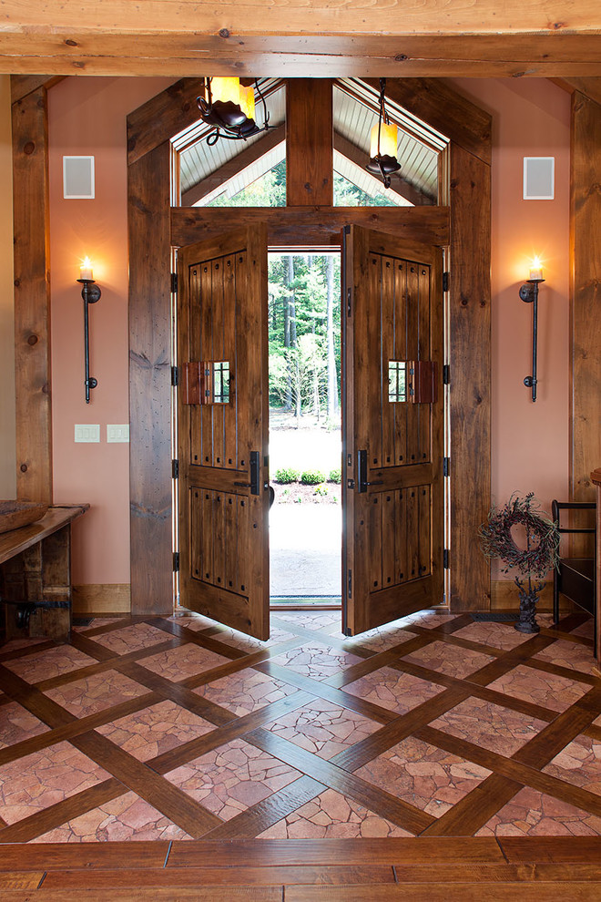 Photo of a country entryway in Other with orange walls, a double front door and a dark wood front door.