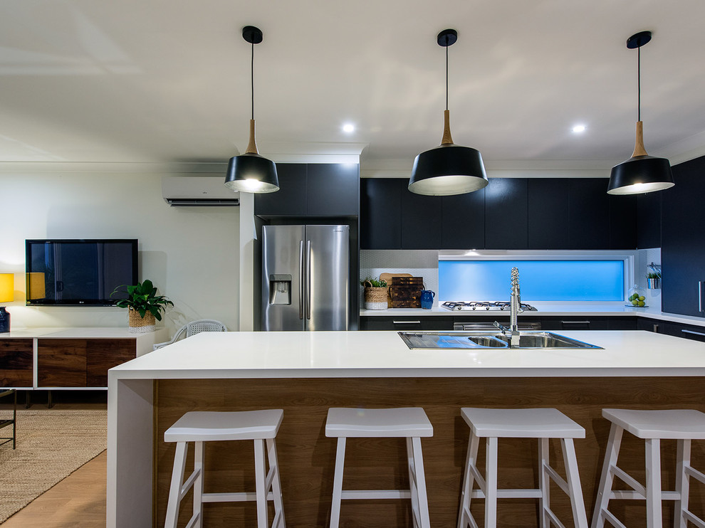 Inspiration for a large contemporary galley open plan kitchen in Brisbane with a double-bowl sink, medium hardwood floors, with island, white benchtop, flat-panel cabinets, black cabinets, quartz benchtops, blue splashback, ceramic splashback, stainless steel appliances and brown floor.