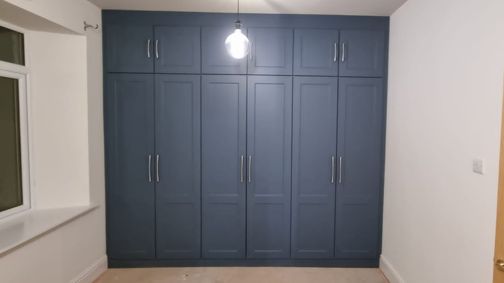 Imagen de armario y vestidor unisex clásico pequeño con a medida, armarios estilo shaker, puertas de armario azules, moqueta y suelo beige