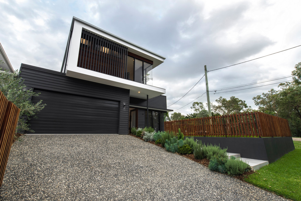Contemporary two-storey black house exterior with a hip roof and a metal roof.