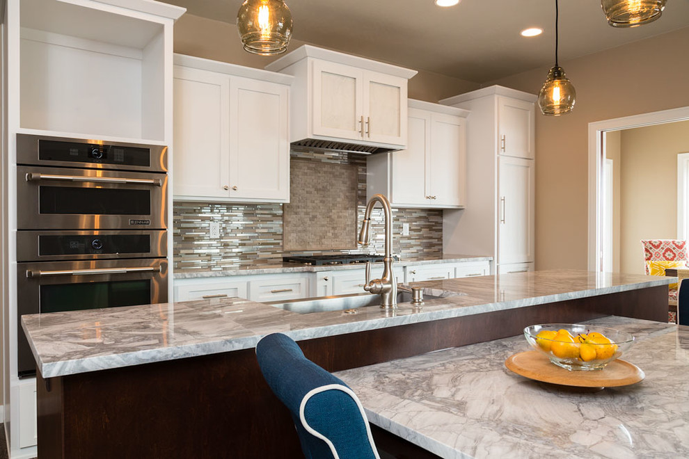Large transitional kitchen photo with an undermount sink, white cabinets, granite countertops, metallic backsplash, glass tile backsplash, stainless steel appliances and recessed-panel cabinets