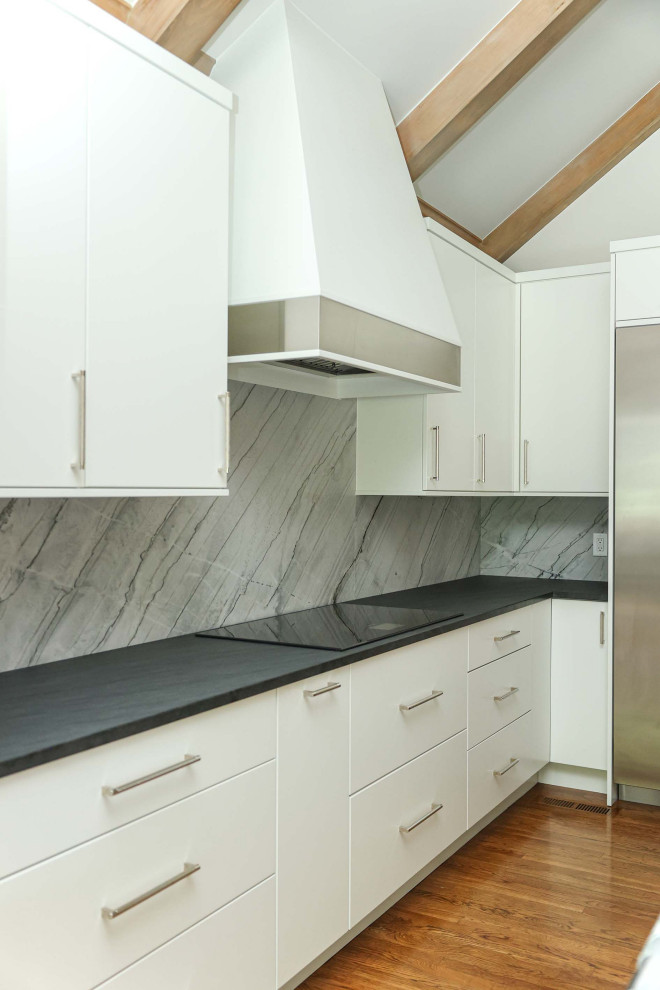 Mid-sized transitional u-shaped medium tone wood floor, brown floor and vaulted ceiling open concept kitchen photo with an undermount sink, flat-panel cabinets, white cabinets, quartzite countertops, gray backsplash, marble backsplash, stainless steel appliances, an island and gray countertops