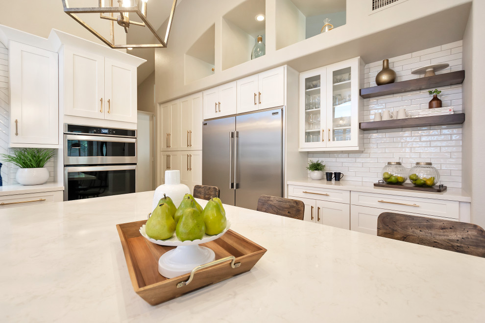 Example of a large transitional u-shaped open concept kitchen design in Phoenix with a farmhouse sink, shaker cabinets, white cabinets, quartz countertops, white backsplash, subway tile backsplash, stainless steel appliances, an island and white countertops