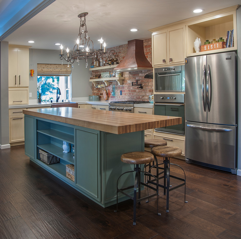 Design ideas for a mid-sized traditional l-shaped open plan kitchen in San Francisco with a farmhouse sink, stainless steel appliances, dark hardwood floors, with island, blue cabinets, quartz benchtops, red splashback and recessed-panel cabinets.