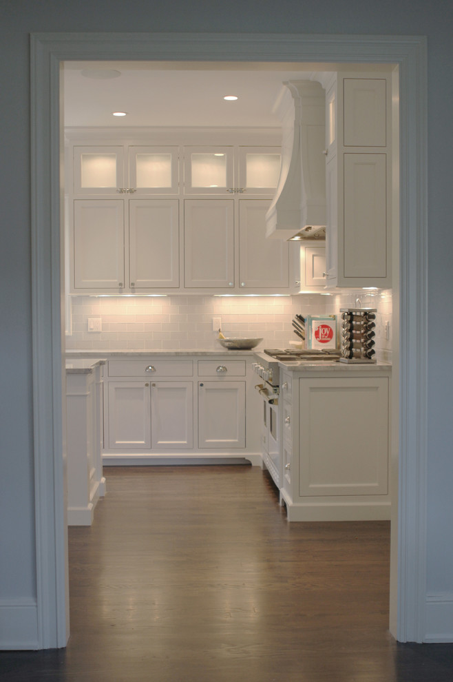 Photo of a mid-sized transitional u-shaped kitchen pantry in New York with flat-panel cabinets, white cabinets, quartzite benchtops, grey splashback, glass tile splashback, stainless steel appliances, dark hardwood floors and with island.