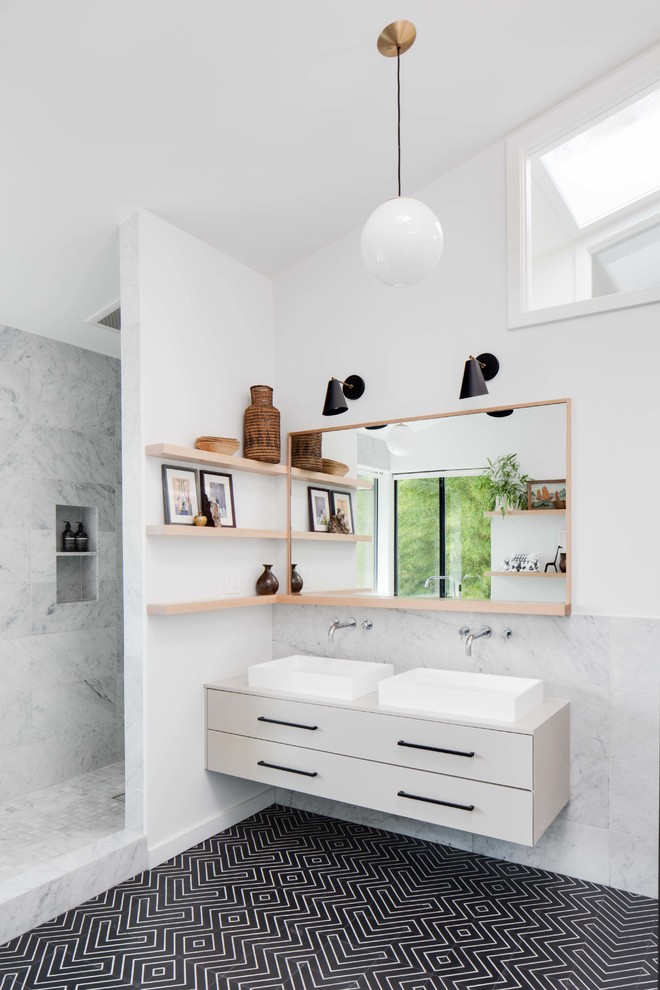 This is an example of a large modern kids bathroom in Los Angeles with flat-panel cabinets, beige cabinets, a freestanding tub, an open shower, a two-piece toilet, white tile, marble, white walls, cement tiles, a vessel sink, black floor and an open shower.
