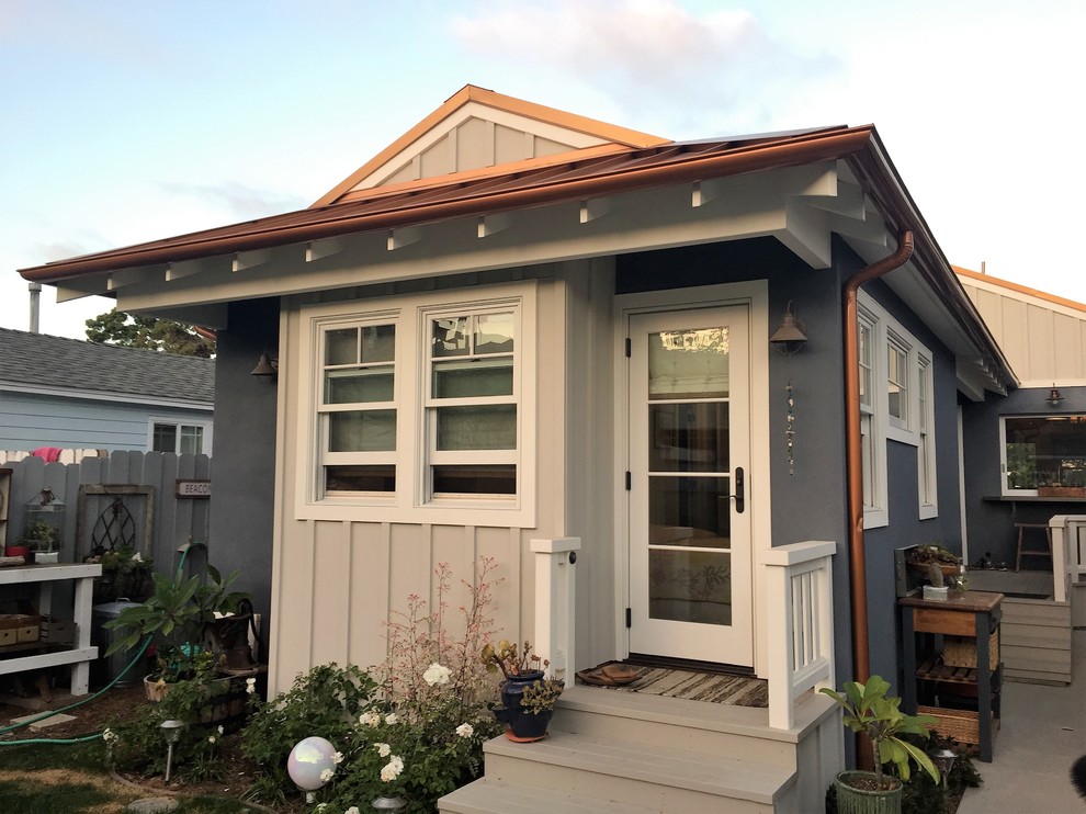 This is an example of a small beach style one-storey blue house exterior in San Diego with concrete fiberboard siding, a clipped gable roof and a metal roof.