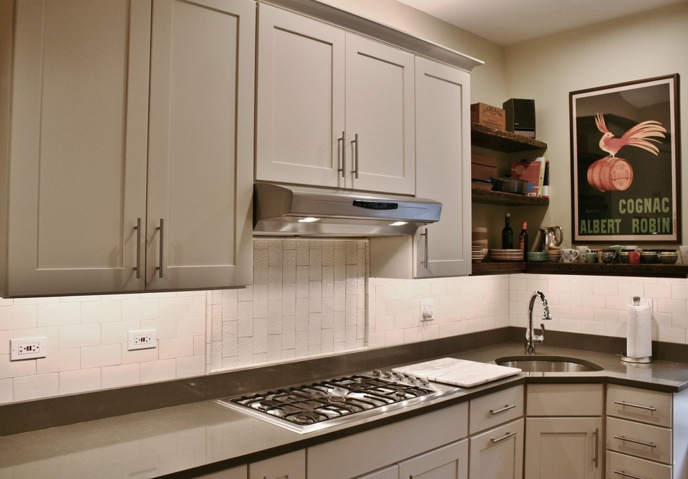 Example of a large transitional u-shaped light wood floor and brown floor enclosed kitchen design in Chicago with an undermount sink, shaker cabinets, white cabinets, quartz countertops, white backsplash, subway tile backsplash, stainless steel appliances and no island