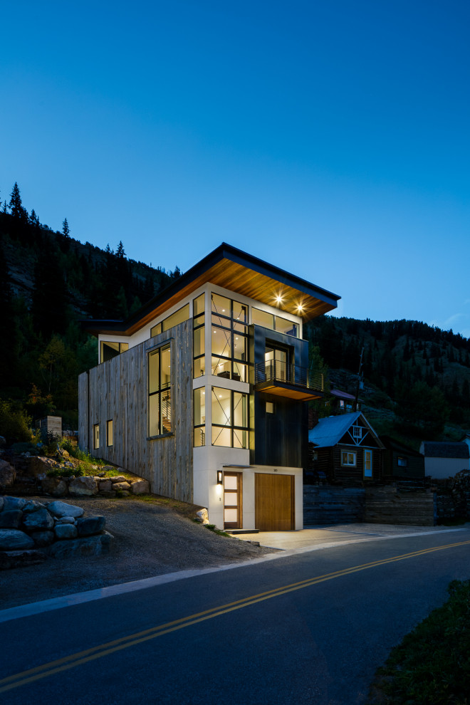 Стильный дизайн: трехэтажный, серый частный загородный дом среднего размера в стиле лофт с комбинированной облицовкой и крышей-бабочкой - последний тренд