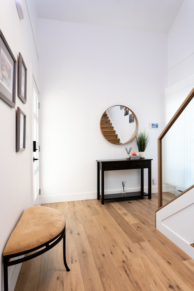 Front door - mid-sized transitional medium tone wood floor and brown floor front door idea in Vancouver with white walls and a glass front door
