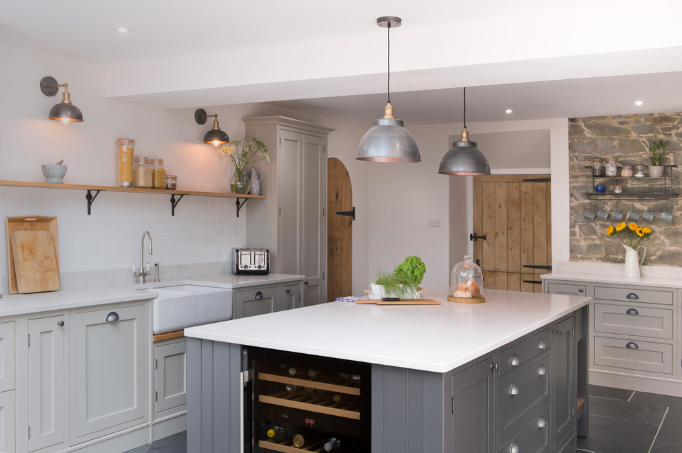 Inspiration for a large country l-shaped eat-in kitchen in Cornwall with a farmhouse sink, grey cabinets, granite benchtops, white splashback, black appliances, slate floors, with island, grey floor, white benchtop and beaded inset cabinets.