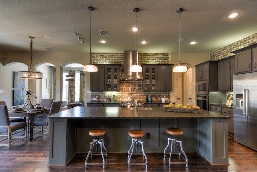 Design ideas for a large industrial l-shaped open plan kitchen in Austin with a farmhouse sink, shaker cabinets, grey cabinets, granite benchtops, brown splashback, subway tile splashback, stainless steel appliances, medium hardwood floors and with island.