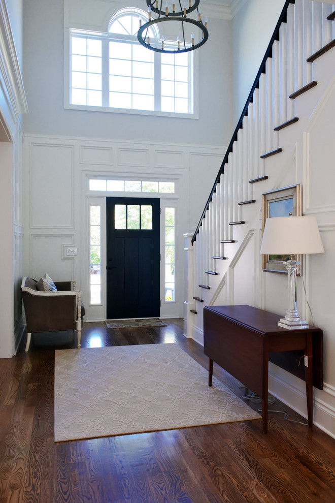 Photo of a traditional foyer in Other with a single front door, a black front door, white walls, dark hardwood floors and brown floor.