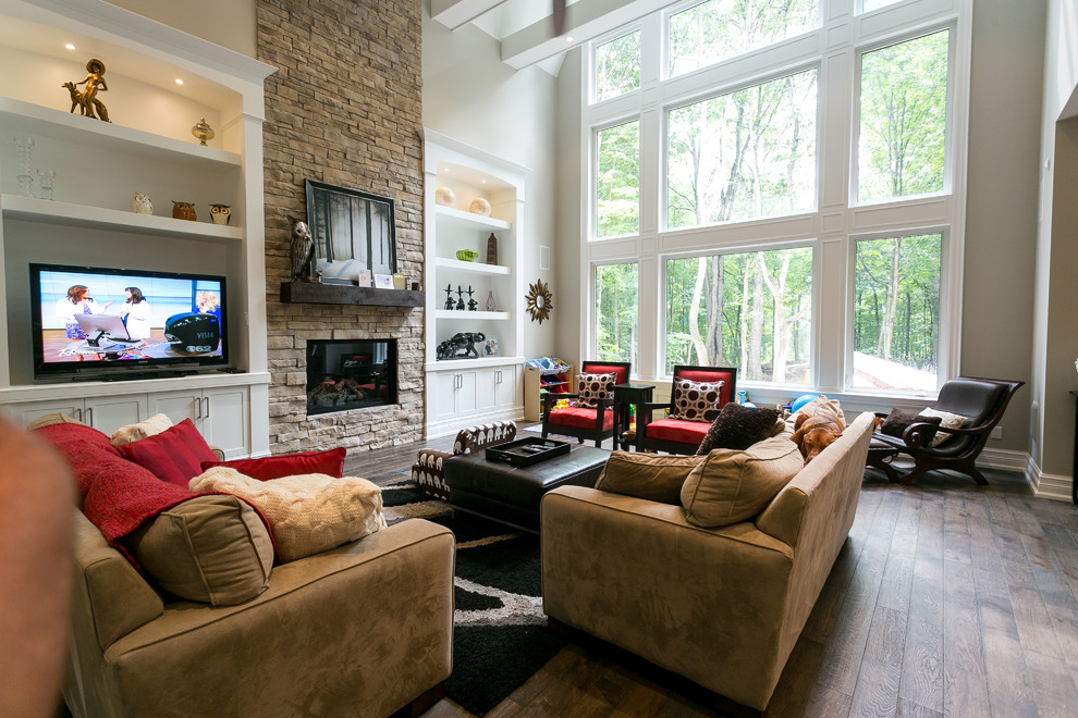 Inspiration for a large transitional open concept living room in Toronto with white walls, dark hardwood floors, a standard fireplace, a stone fireplace surround, a wall-mounted tv and brown floor.
