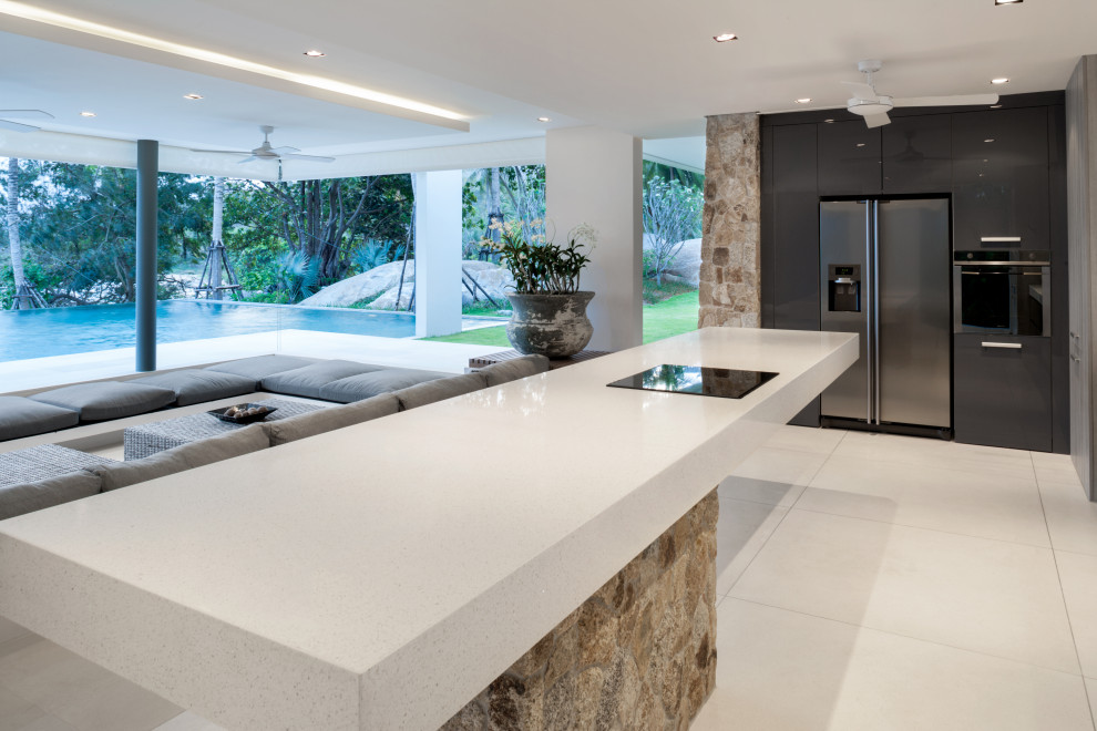 Inspiration for a large modern l-shaped open plan kitchen in Malaga with an undermount sink, flat-panel cabinets, black cabinets, quartz benchtops, stainless steel appliances, porcelain floors, with island, beige floor and white benchtop.