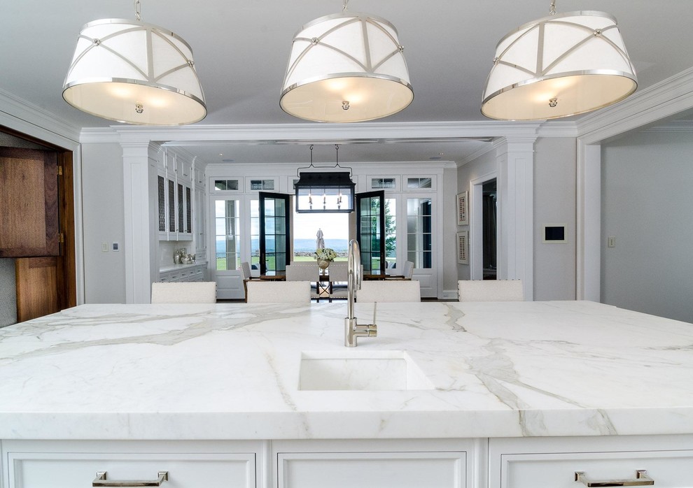 Large transitional l-shaped eat-in kitchen in San Francisco with an undermount sink, recessed-panel cabinets, white cabinets, marble benchtops, white splashback, dark hardwood floors, with island, brown floor and white benchtop.