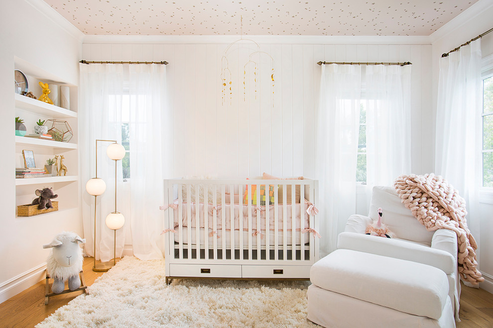 This is an example of a mid-sized midcentury nursery in Los Angeles with white walls, light hardwood floors and yellow floor.