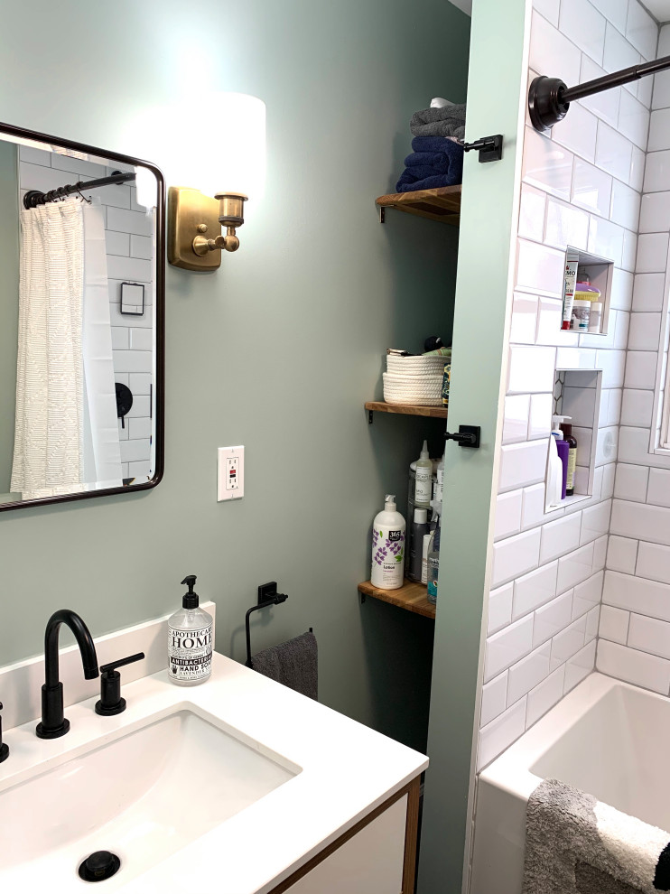 Inredning av ett modernt litet vit vitt en-suite badrum, med släta luckor, vita skåp, ett badkar i en alkov, en dusch/badkar-kombination, en toalettstol med hel cisternkåpa, vit kakel, keramikplattor, gröna väggar, klinkergolv i keramik, ett undermonterad handfat, bänkskiva i kvarts, svart golv och dusch med duschdraperi