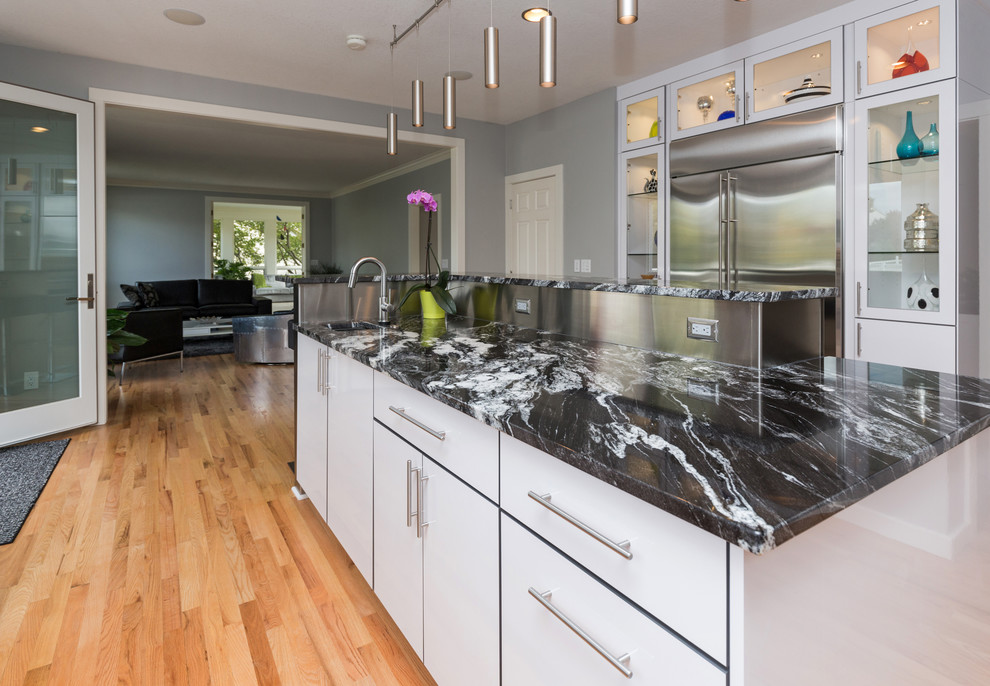 Open concept kitchen - large contemporary u-shaped light wood floor open concept kitchen idea with an undermount sink, flat-panel cabinets, white cabinets, granite countertops, multicolored backsplash, mosaic tile backsplash, stainless steel appliances and an island