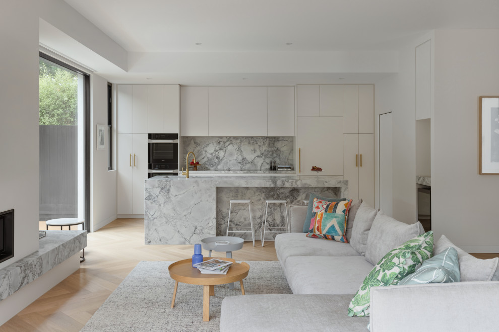 Design ideas for a contemporary open concept living room in Melbourne with white walls, light hardwood floors, a standard fireplace and beige floor.