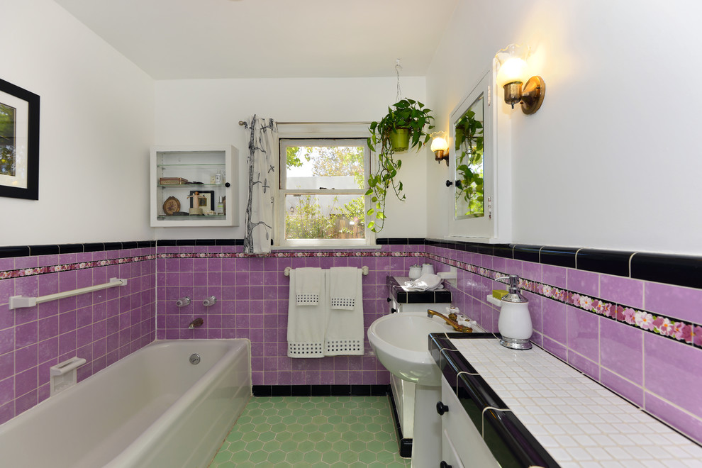 Inspiration for a large mediterranean master bathroom in San Diego with a pedestal sink, flat-panel cabinets, white cabinets, tile benchtops, a corner tub, a corner shower, a one-piece toilet, white tile, ceramic tile, purple walls and mosaic tile floors.