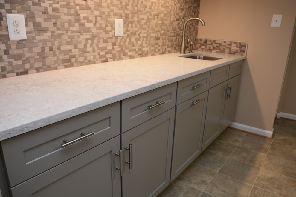 Design ideas for a mid-sized traditional single-wall wet bar in Baltimore with an undermount sink, recessed-panel cabinets, grey cabinets, quartz benchtops, grey splashback, ceramic splashback, beige floor and white benchtop.