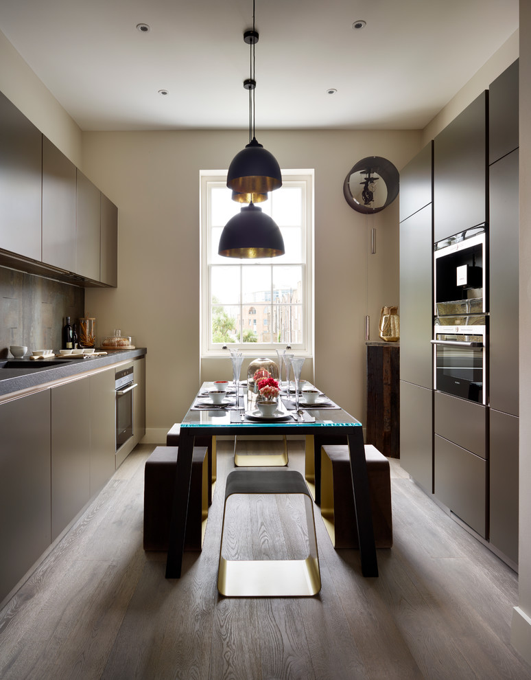 This is an example of a mid-sized contemporary galley eat-in kitchen in Essex with an undermount sink, flat-panel cabinets, grey cabinets, grey splashback, panelled appliances, medium hardwood floors and no island.