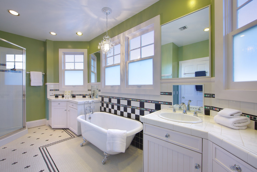 Photo of a large transitional master wet room bathroom in Other with beaded inset cabinets, white cabinets, a claw-foot tub, white tile, ceramic tile, green walls, mosaic tile floors, a drop-in sink, tile benchtops, a hinged shower door and white benchtops.