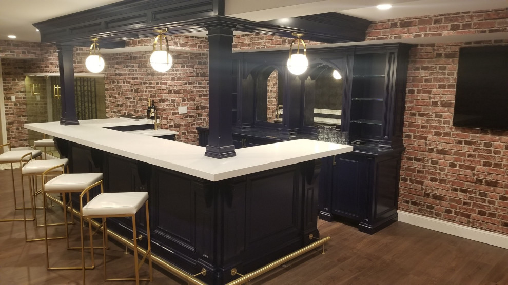 Inspiration for a large transitional u-shaped seated home bar in New York with an undermount sink, blue cabinets, quartzite benchtops, laminate floors, brown floor and white benchtop.