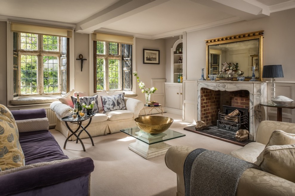 Large traditional formal enclosed living room in Wiltshire with beige walls, carpet, a standard fireplace, a stone fireplace surround and beige floor.