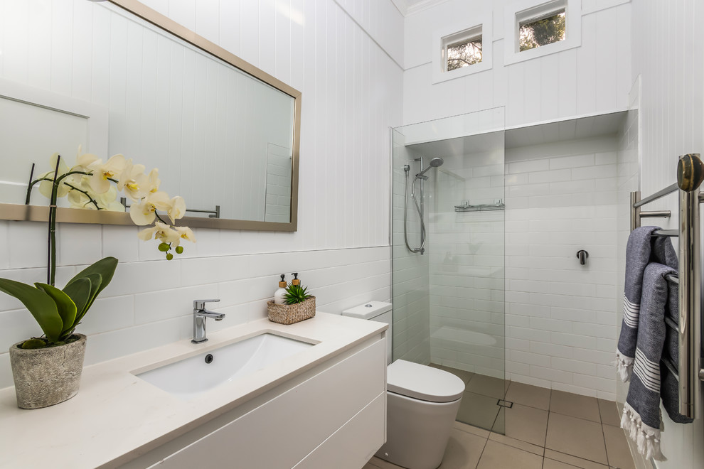 Beach style bathroom in Brisbane with flat-panel cabinets, white cabinets, an alcove shower, white tile, white walls, an undermount sink, grey floor, an open shower and white benchtops.